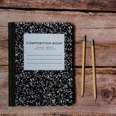 Composition book on desk with two pencils.